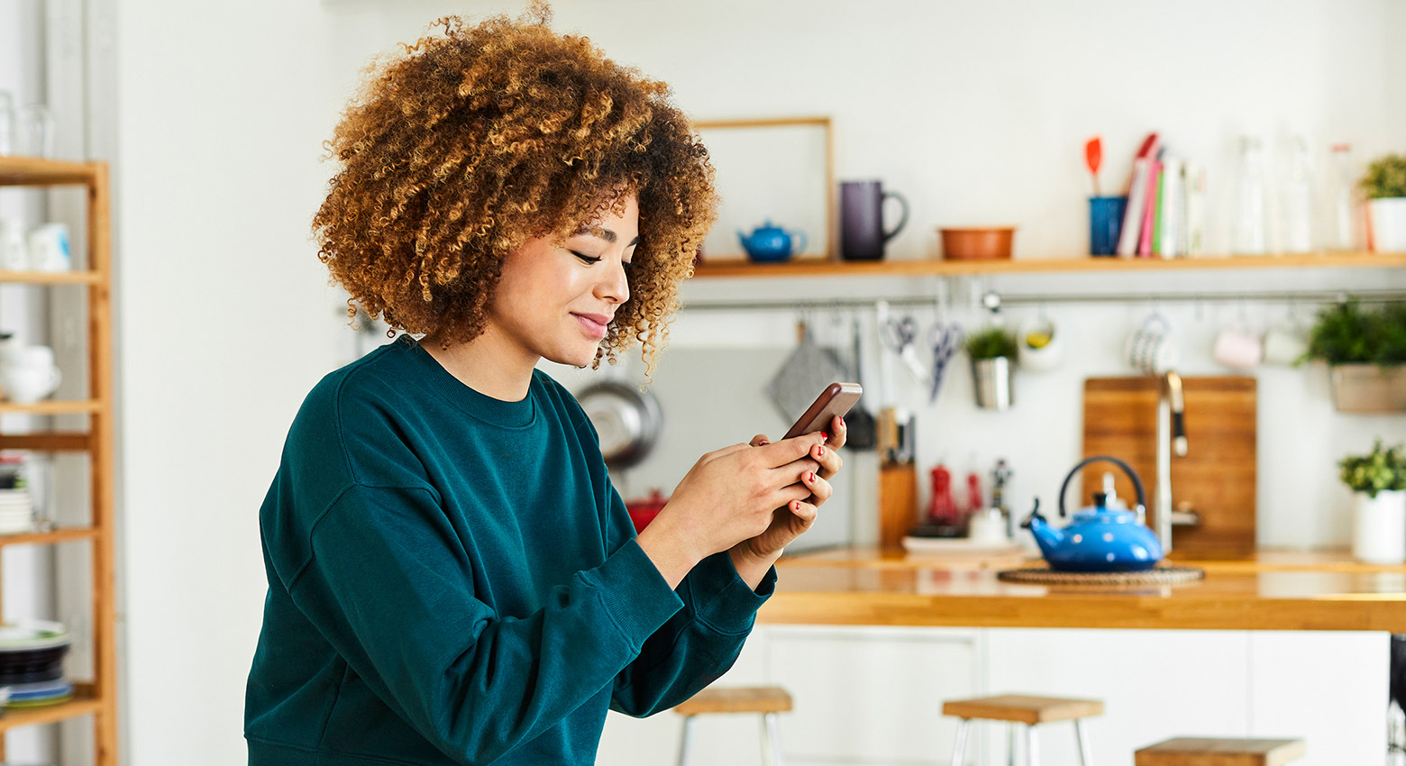 Une femme regarde son téléphone dans la cuisine