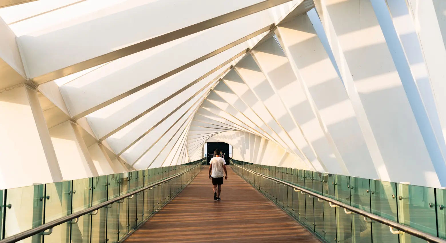 Personne marchant sur un pont entre une architecture moderne. 