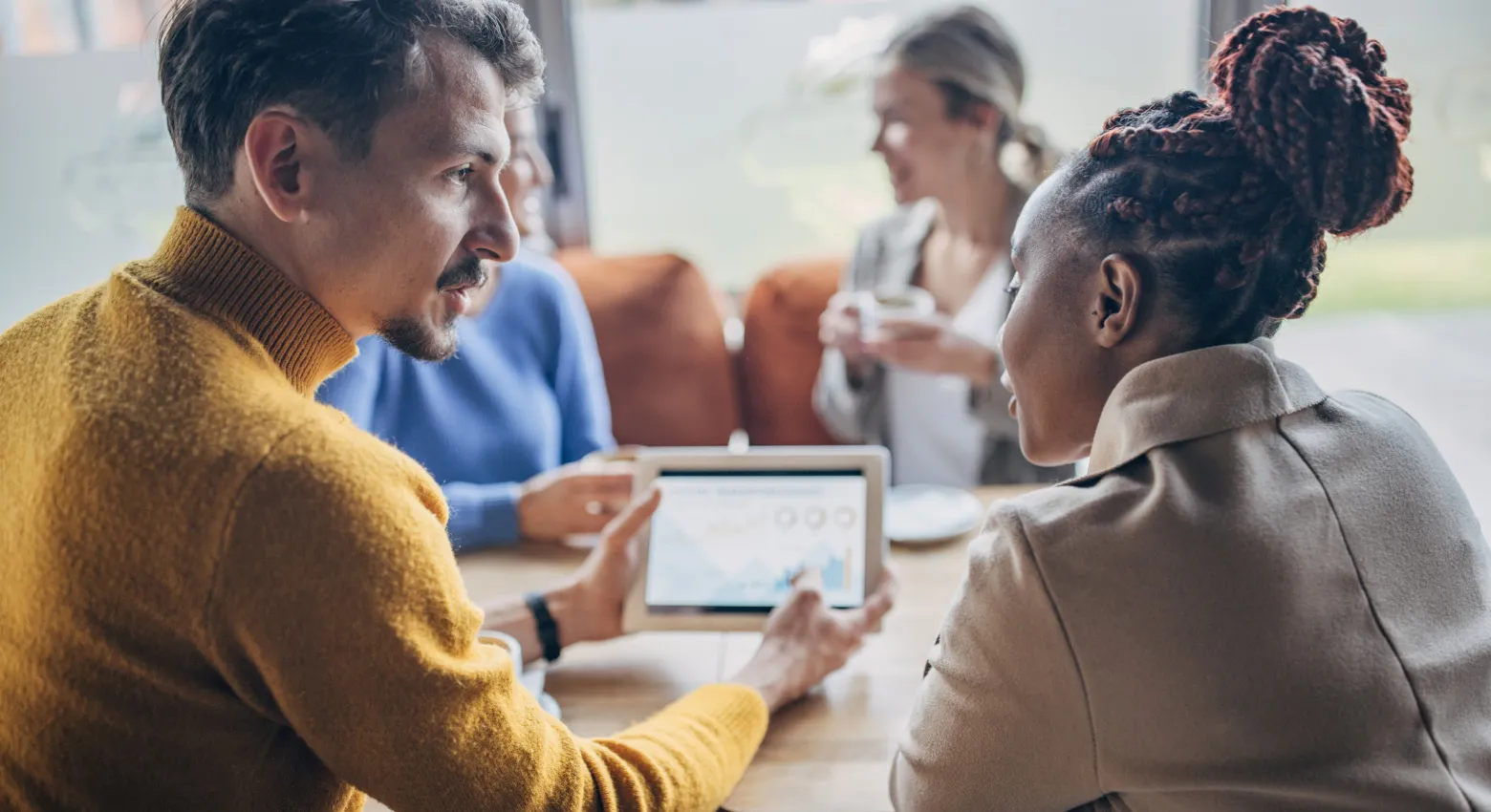 personnes partageant une table avec une tablette