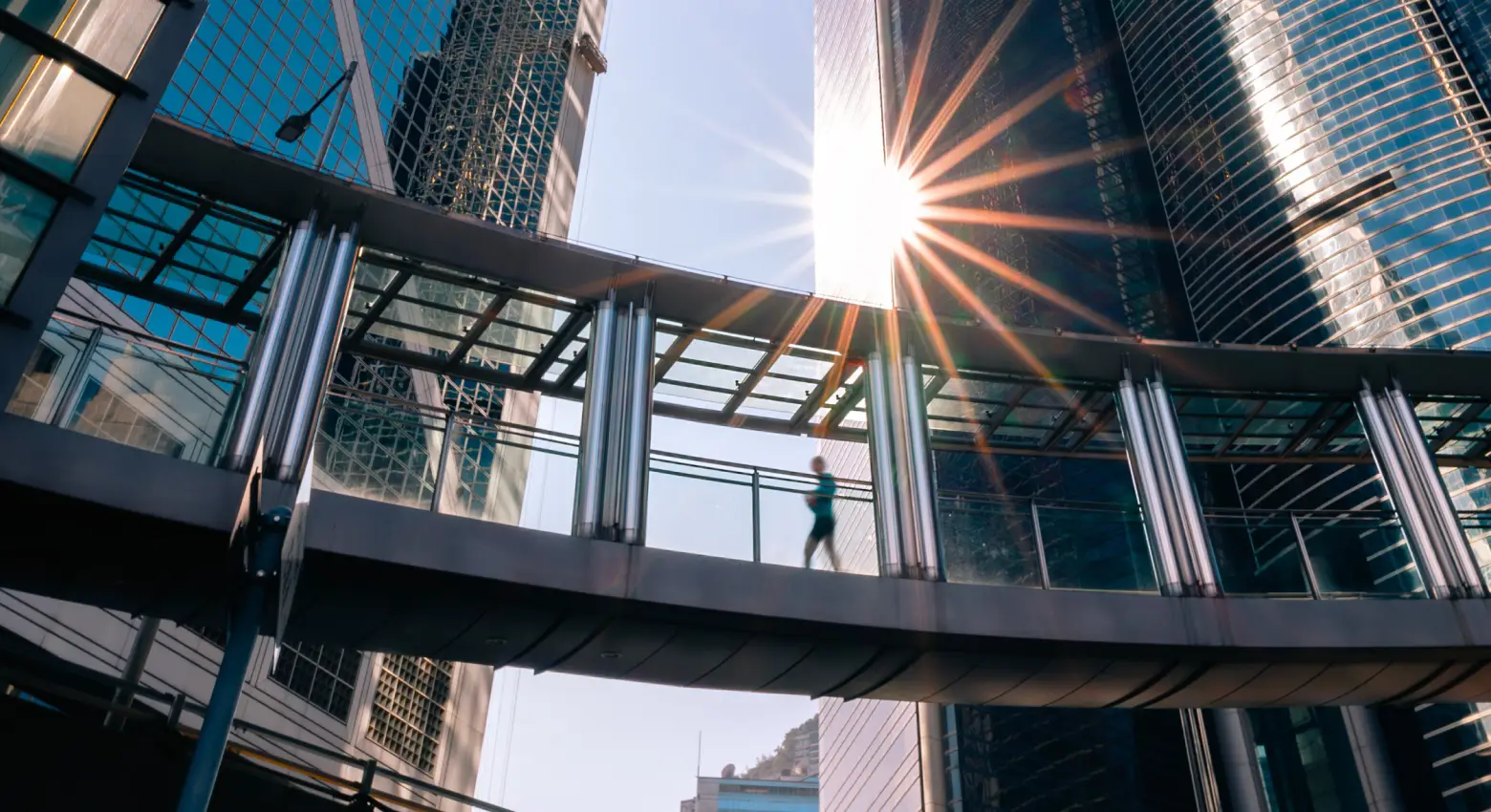 Personne marchant sur un pont entre une architecture moderne. 