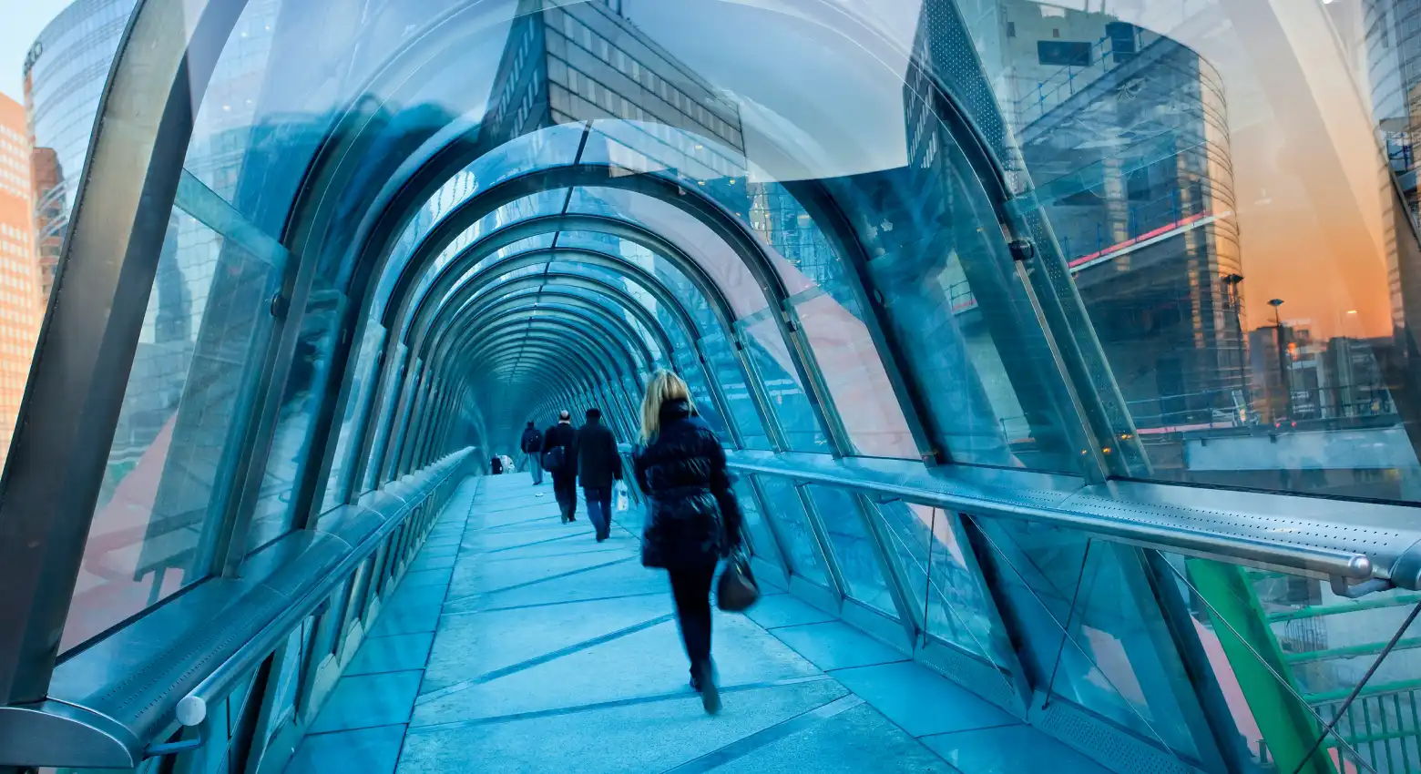 Des personnes marchent sur un pont entre de l'architecture moderne 