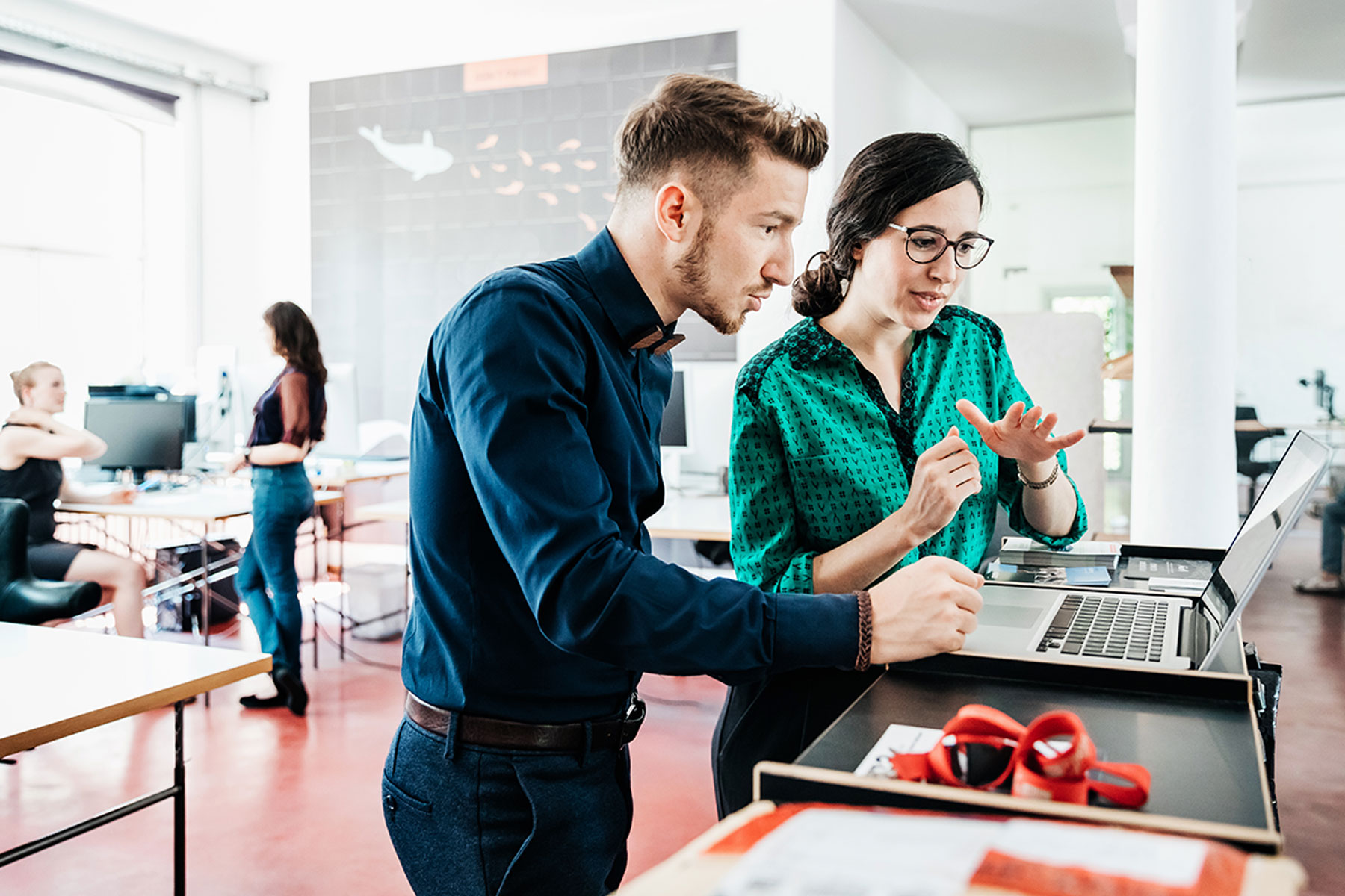 Une femme et un homme discutent de confidentialité en regardant un ordinateur portable.