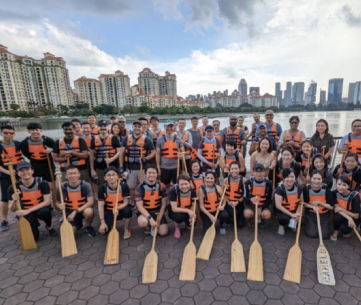 Groupe d'employés en gilet de sauvetage tenant des pagaies devant un lac